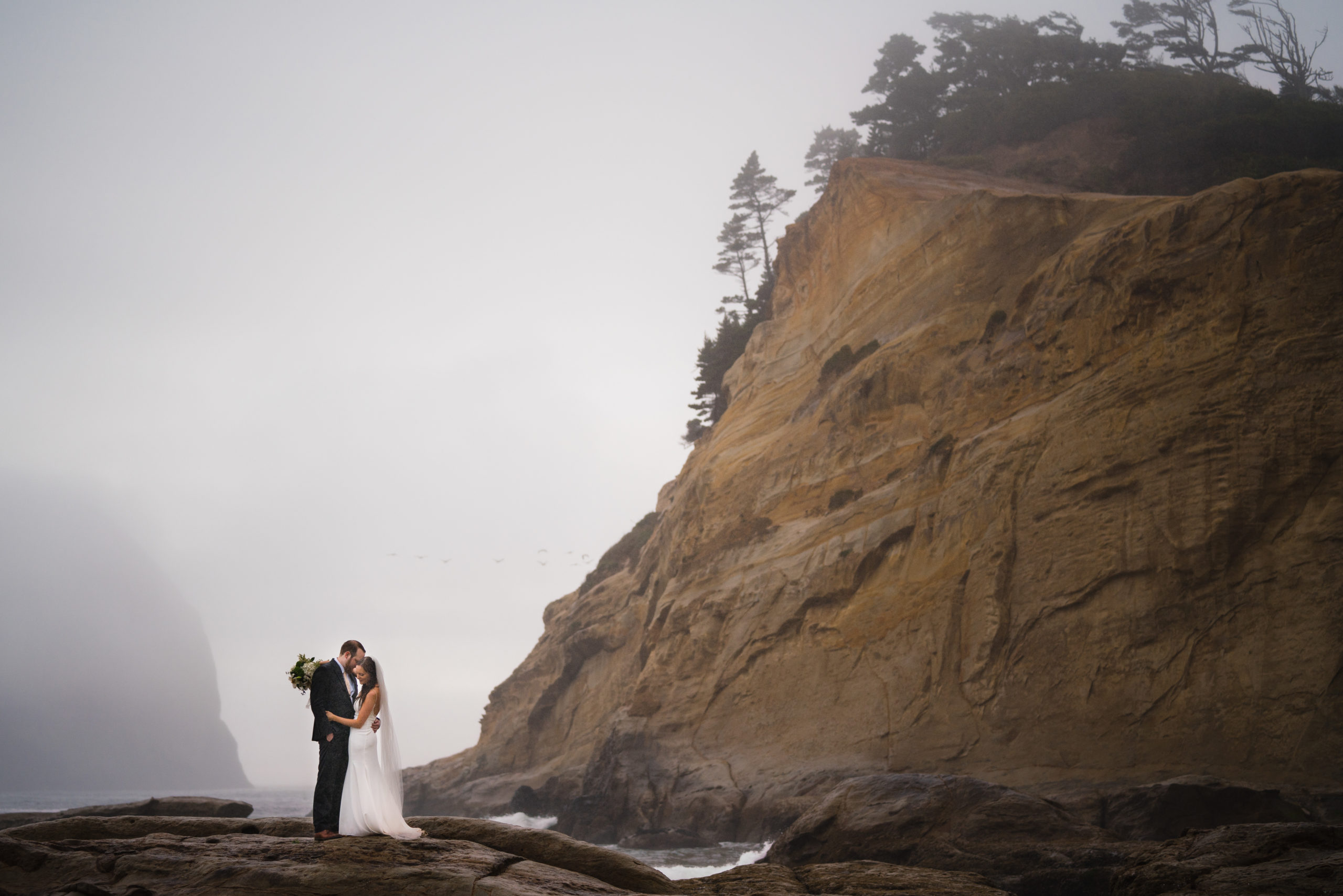 couple posing for portraits during their elopement at cape kiwanda